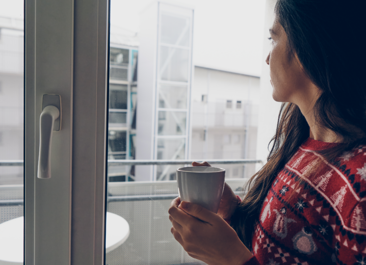 mulher em frente de uma janela antirruido tomando seu café