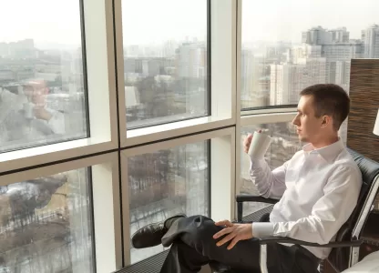 Homem apreciando a vista em apartamento silencioso graças à vedação termoacústica em janelas panorâmicas.