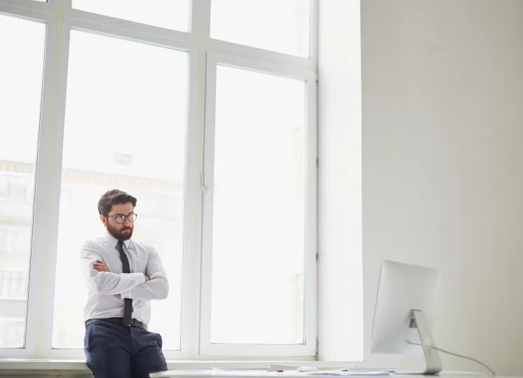 Homem em escritório moderno com grandes janelas antirruído para home office, transmitindo conforto e silêncio no ambiente de trabalho.