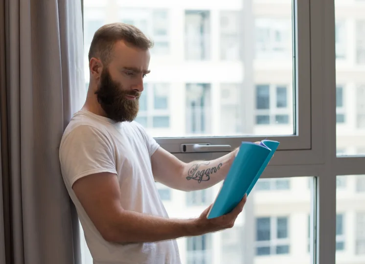 Homem em apartamento silencioso ao lado de janela acústica que demonstra que janela acústica funciona contra ruído externo